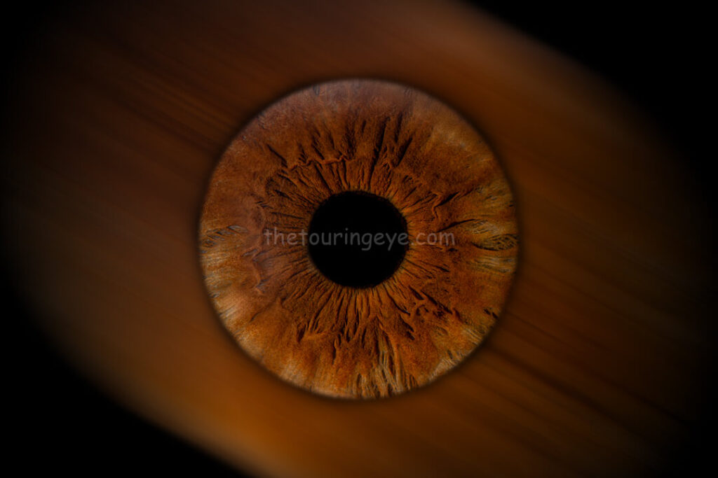 A brown eye iris hand edited to portray a blurred background effect. Eye art. Iris art. Hand edited artwork. Eye photography. Iris photography. The Touring Eye.